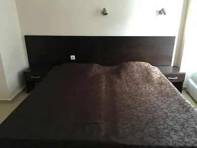 a bed with a brown bedspread on top of it at Elite Apartments is located in the old town of Pomorie in Pomorie