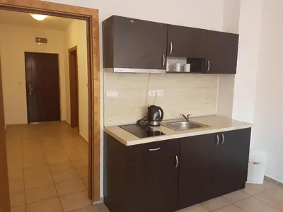 a kitchen with black cabinets and a sink and a hallway at Salt Lake ApartHotel in Pomorie