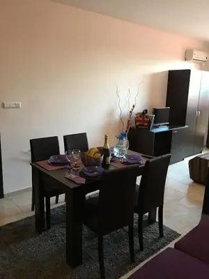 a dining room with a table with chairs and a kitchen at Salt Lake ApartHotel in Pomorie