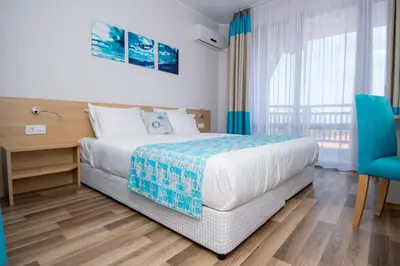 a bedroom with a bed and a blue chair at Nevis Resort & Aqua Park - All Inclusive in Sunny Beach