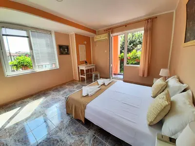 a bedroom with a large bed and two windows at Art Villa Rozalia in Ravda