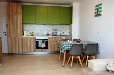 a kitchen with green cabinets and a table with chairs at Green Life One-Bedroom Apartment with Sea View by Flаt Manаger in Sozopol