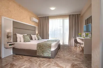 a hotel room with a bed and a television at Marine Beach Sands- All Inclusive in Obzor