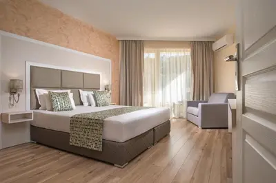 a hotel room with a large bed and a chair at Marine Beach Sands- All Inclusive in Obzor