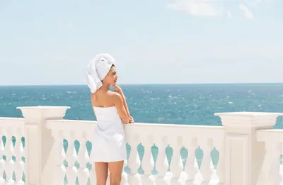 a woman in a white dress leaning on a fence at Marine Beach Sands- All Inclusive in Obzor