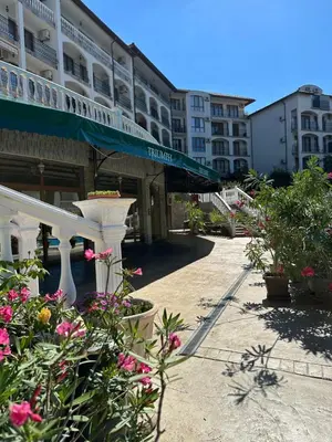a courtyard of a building with flowers and a balcony at Аппартамент в Триумфе Святой Влас 300м от моря, бассейн. in Sveti Vlas