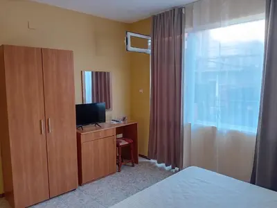 a bedroom with a bed and a desk with a television at Solis in Primorsko