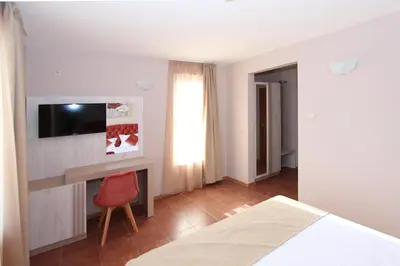 a bedroom with a bed and a desk and a television at Hotel PERLA BEACH in Sozopol