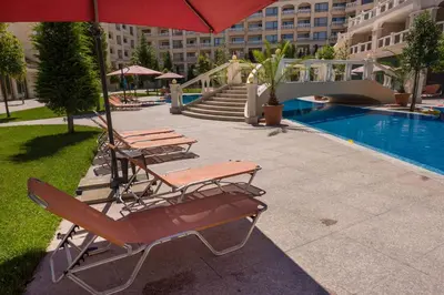 a group of chairs and an umbrella next to a pool at Blue Lagoon Seafront Apartments in Varna City