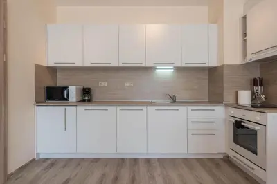 a white kitchen with white cabinets and a microwave at Blue Lagoon Seafront Apartments in Varna City