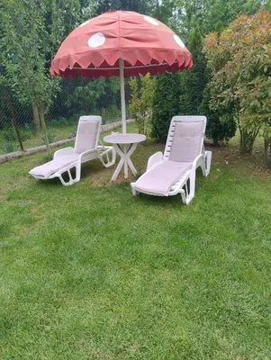 two chairs and a table with an umbrella in a yard at Къща за гости АКАЦИЯ in Ravna Gora