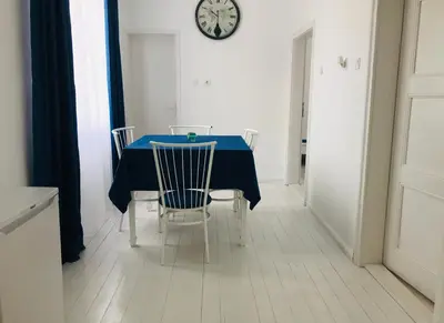 a dining room table with chairs and a clock on the wall at Къща Наде in Tsarevo