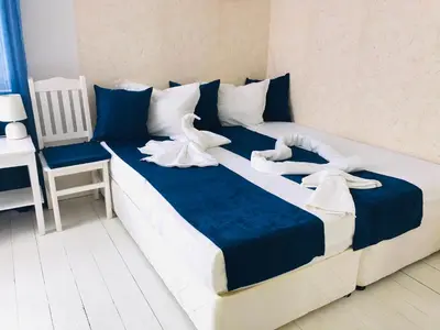 a large bed with blue and white sheets and a chair at Къща Наде in Tsarevo