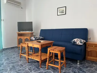 a living room with a blue couch and a table at Студио Одеса 22 in Sozopol