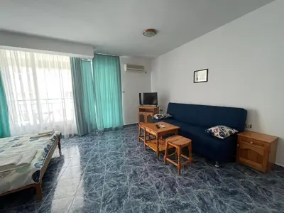 a living room with a blue couch and a bed at Студио Одеса 22 in Sozopol
