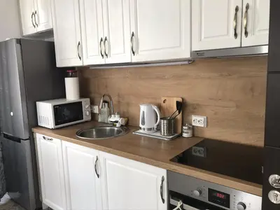 a kitchen with white cabinets and a sink and a microwave at Sunny Shore Burgas Apartment in Burgas City