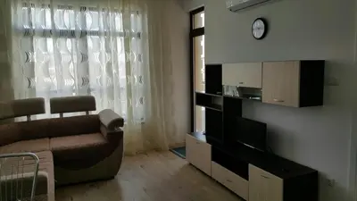 a living room with a couch and a clock on the wall at Айвазовский парк in Pomorie