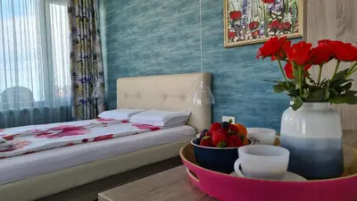 a bedroom with a bed and a vase with red flowers at Villa Flora in Sozopol