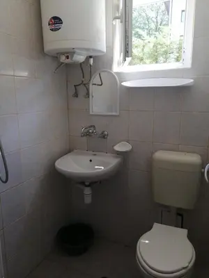 a bathroom with a toilet and a sink and a window at Ваканционно селище СБХ in Shkorpilovtsi