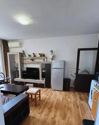 a living room with a table and a refrigerator at Marina Bay Apart Saint Vlas in Sveti Vlas