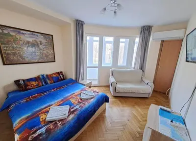 a bedroom with a king sized bed and a chair at Варна Хостел in Varna City