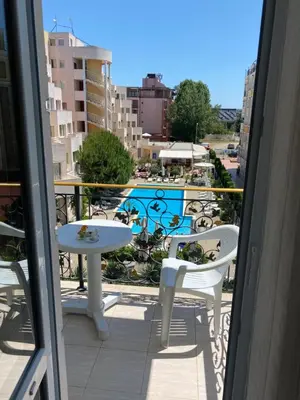 a balcony with a table and chairs and a pool at Апартамент на солнечном берегу in Sunny Beach