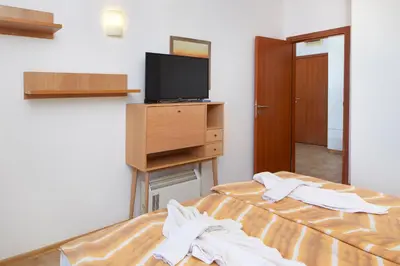a bedroom with a bed with a tv and a bedskirts at Infinity Terrace 1BR Apartment Nessebar in Nesebar