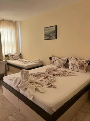 two twin beds in a room with a window at Guest Rooms Nia Elis Kiten in Burgas City