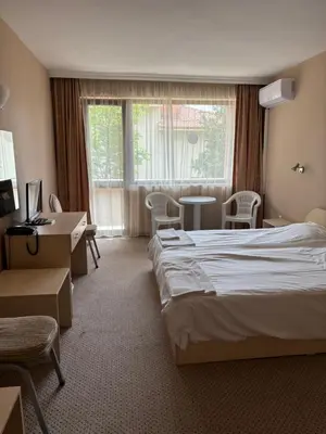 a hotel room with a bed and a desk and a window at Relax Guest House in Burgas City