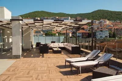 a rooftop patio with couches and chairs on a building at Луксозен апартамент Свети Влас Вила Аристо in Sveti Vlas