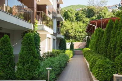 a walkway in front of a building with trees at Луксозен апартамент Свети Влас Вила Аристо in Sveti Vlas