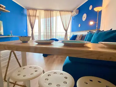 a dining room table with chairs and a blue wall at Свети Зосим in Sozopol