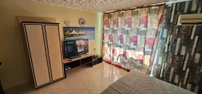 a room with a television and a wall with curtains at Курортно студио in Sunny Beach