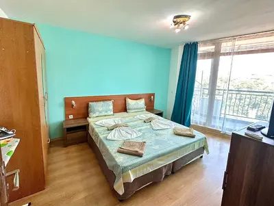 a bedroom with a large bed with blue walls at Апартаменти Зафи in Sozopol