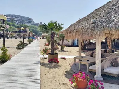 a beach with a wooden walkway and a straw umbrella at Dolce Vita sea view apartment in Sveti Vlas