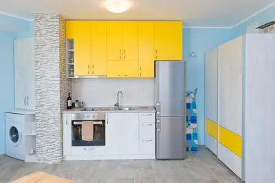 a kitchen with yellow cabinets and a stainless steel refrigerator at Апартамент в жълто in Burgas City