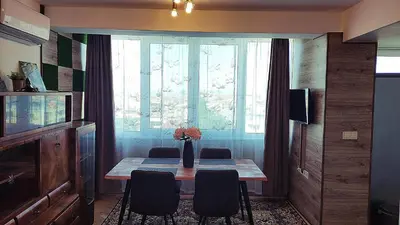 a dining room table with chairs and a large window at Апартамент за гости ВО1 in Burgas City