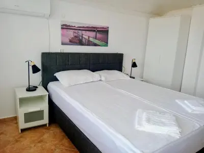 a bedroom with a large white bed and a night stand at Vila Rosen in Lozenets