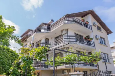 a tall white building with balconies and trees at Vila Rosen in Lozenets