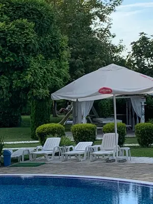 a white umbrella and chairs next to a pool at Sozopoli Hills Apartment A6 in Sozopol