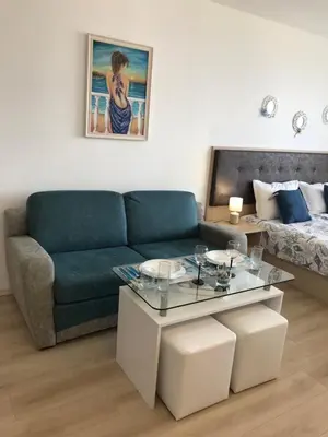 a living room with a couch and a table at Студио Сънрайз А28, Лозенец in Lozenets