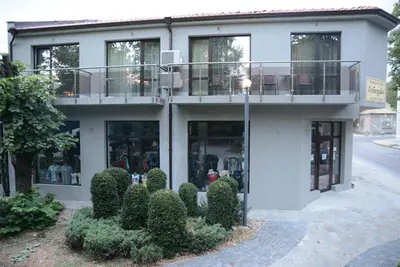 a white building with a balcony and some bushes at Стаи за гости Гебедже in Beloslav