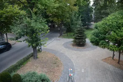 a bike parked on a sidewalk in a park with trees at Стаи за гости Гебедже in Beloslav