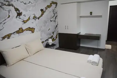 a bedroom with a white bed and a desk at Стаи за гости Гебедже in Beloslav