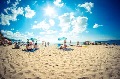a group of people sitting on a beach with umbrellas at Sea View Panoramic Apartments, Fort Noks Crown Club in Sveti Vlas