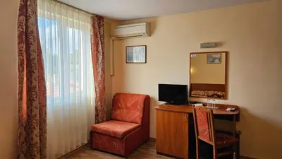 a room with a chair and a desk and a mirror at Caprice Family Hotel in Varna City