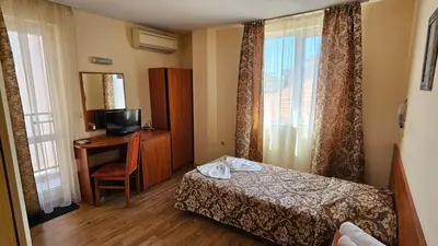 a hotel room with a bed and a desk with a television at Caprice Family Hotel in Varna City