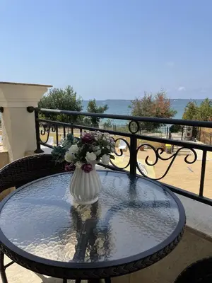 a vase with flowers sitting on a table on a balcony at Horizon Katrina Apartments - Sea line & Beach Access in Sveti Vlas