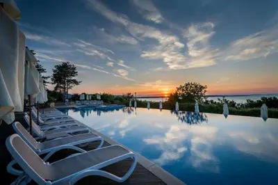 a group of lounge chairs sitting next to a swimming pool at Santa Marina resort Sozopol - penthouse with amazing sea view in Sozopol