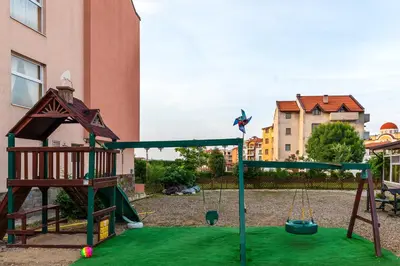 a playground with a swing set in a yard at House Apartments Black sea Hotel in Obzor